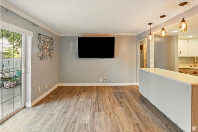 Unfurnished living room featuring light wood finished floors, baseboards, and crown molding | Image 5