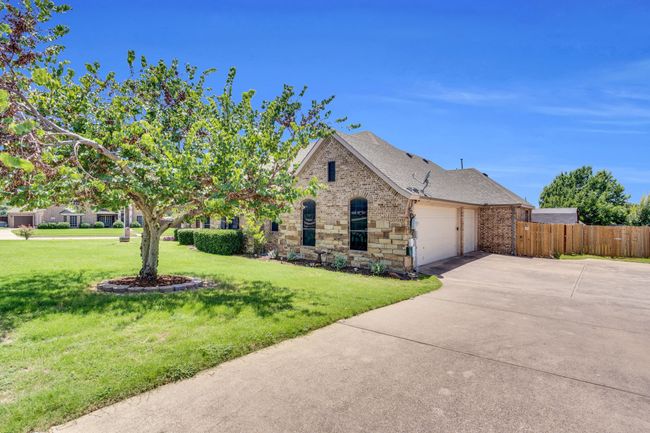 View of front of house featuring an attached garage, concrete driveway, roof with shingles, and brick siding | Image 39