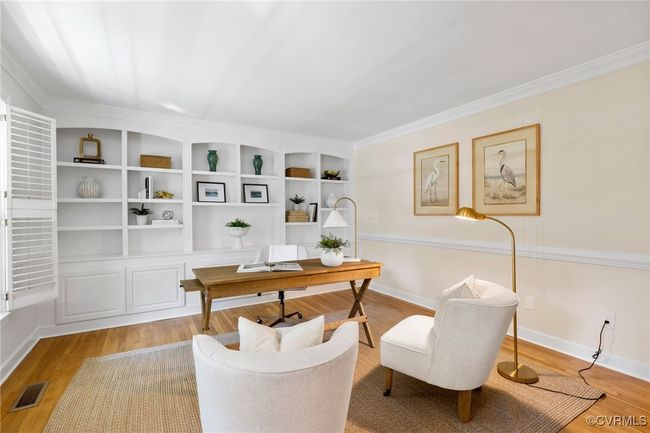 Formal Living room as a home office with beautiful built-in shelving and cabinets, hardwood flooring, crown molding, chair rail and plantation shutters. There are double doors offering privacy if you wish. | Image 7
