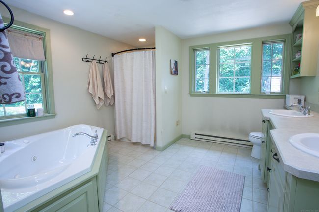 Luxurious primary bathroom with double sinks, built-in cupboards, whirlpool tub, shower and loads of windows overlooking the beautiful private backyard. | Image 25