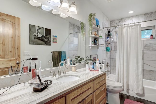 Bathroom featuring shower / bath combination with curtain, vanity, and toilet | Image 38