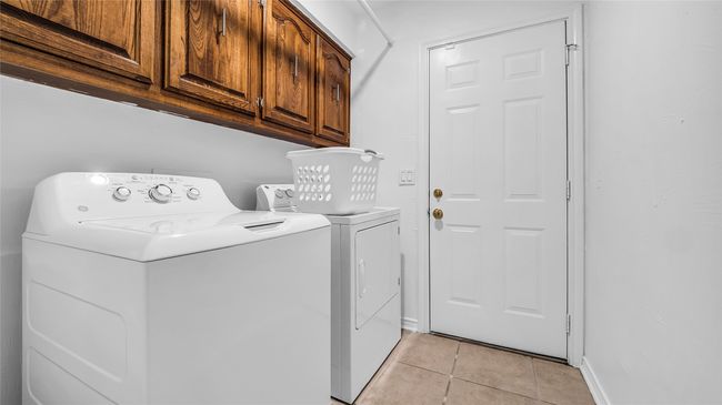 Washroom with cabinet space, light tile patterned floors, and washing machine and clothes dryer | Image 4
