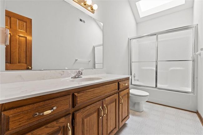 Full bathroom featuring vanity, toilet, lofted ceiling with skylight, and enclosed tub / shower combo | Image 31