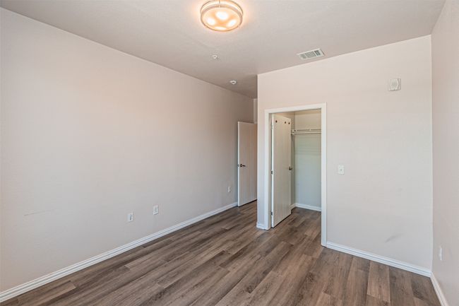Unfurnished bedroom featuring wood finished floors, a walk in closet, and a closet | Image 12