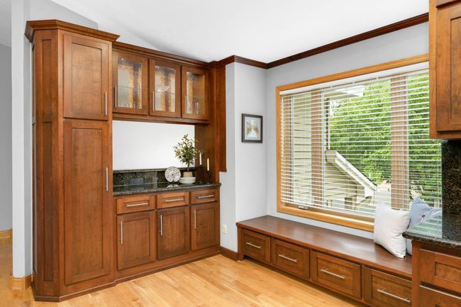 Beautiful woodwork shapes this kitchen nook with an airy bench and additional pantry/bar space. | Image 9