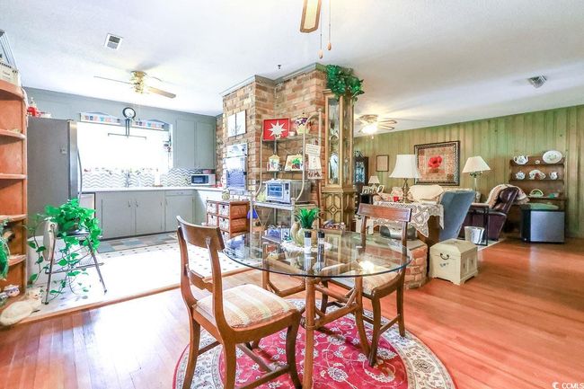 Dining room featuring ceiling fan, light wood-type flooring, and wood walls | Image 14