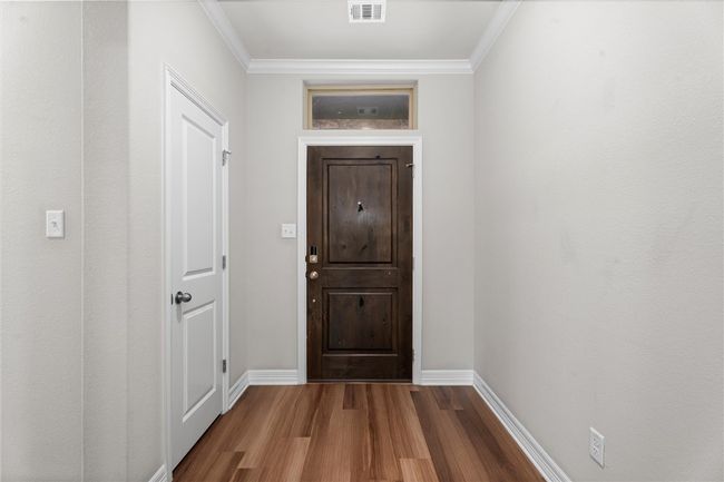 Hall with visible vents, ornamental molding, baseboards, and wood finished floors | Image 4