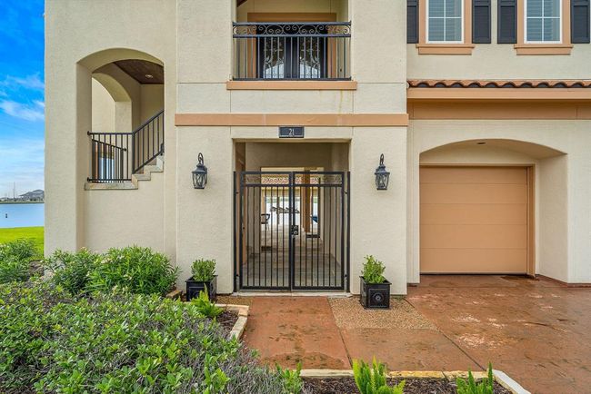 This waterfront home offers a ground-level entry framed by lush landscaping. Pass through the wrought-iron gates to the left, leading to the entry stairway, or continue straight to the dockside living area on the ground level | Image 37