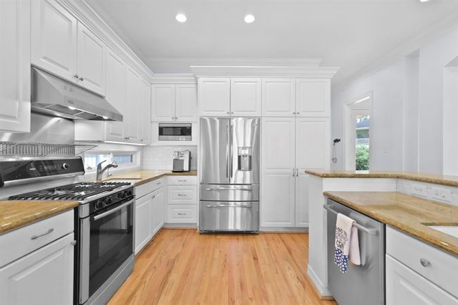 This side of the kitchen features a sleek refrigerator, built-in microwave, and ample storage. | Image 21