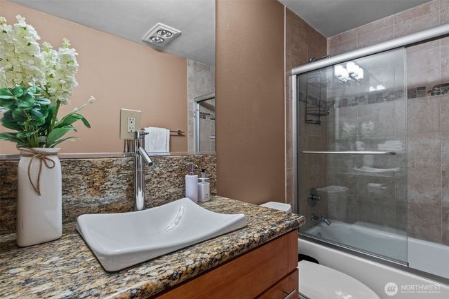 The Main bathroom is in a class all it own. This full bath also has glass shower doors, heated tile flooring, slab granite countertops, a lovely, top-mount sink, AND a combo washer/dryer! | Image 26