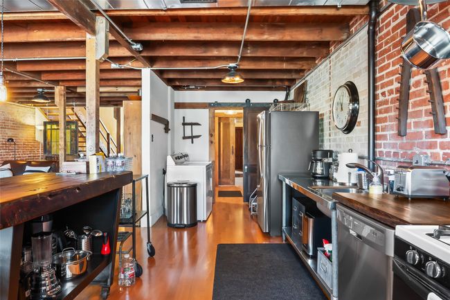 Kitchen featuring stainless steel appliances, washing machine and dryer, brick wall, and a barn door | Image 17