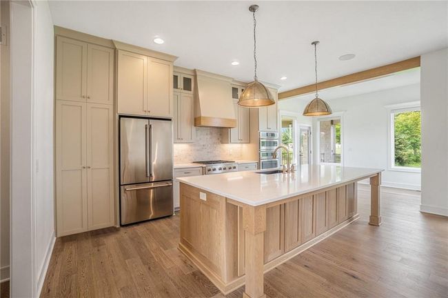 Kitchen with stainless steel appliances, premium range hood, a sink, light wood finished floors, and recessed lighting | Image 24