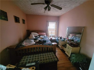 Bedroom with ceiling fan, hardwood / wood-style flooring, and a textured ceiling | Image 3