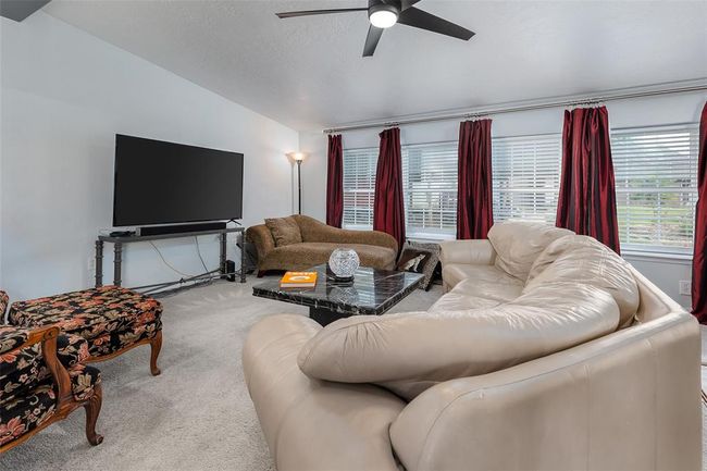 Carpeted living room with ceiling fan and vaulted ceiling | Image 8