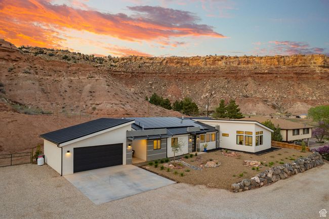 View of front facade with stucco siding, driveway, solar panels, metal roof, and fence | Image 60
