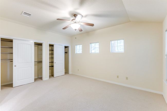 Unfurnished bedroom featuring light carpet, two closets, a ceiling fan, and lofted ceiling | Image 21