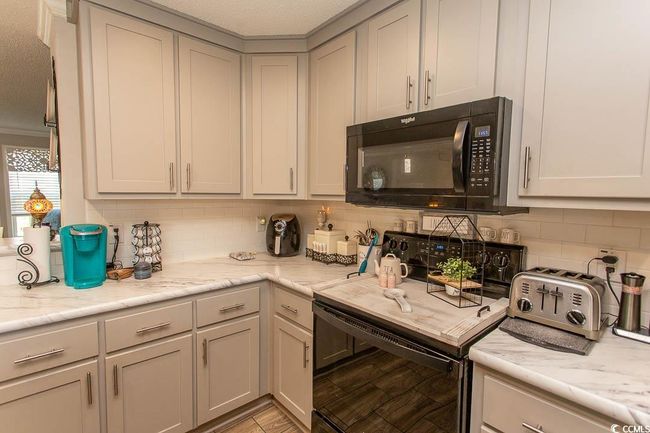 Kitchen with a textured ceiling, tasteful backsplash, black microwave, a toaster, and gray cabinets | Image 9