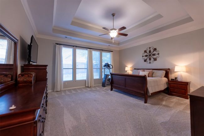 Bedroom featuring a raised ceiling, light carpet, ornamental molding, and ceiling fan | Image 20