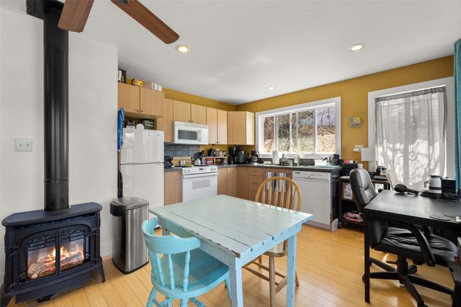 Kitchen featuring light brown cabinets, light wood-style floors, white appliances, a wood stove, and recessed lighting | Image 32