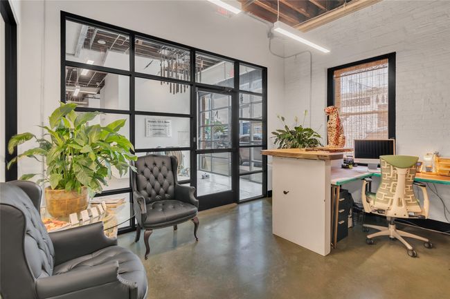 Office area with a high ceiling, finished concrete floors, and brick wall | Image 8