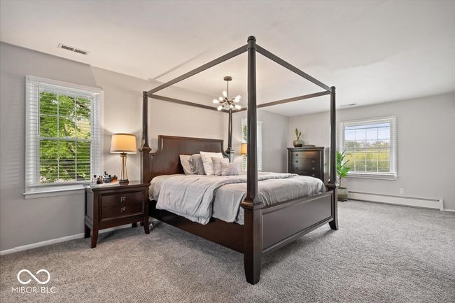 carpeted bedroom featuring a baseboard radiator, a chandelier, and baseboards | Image 23