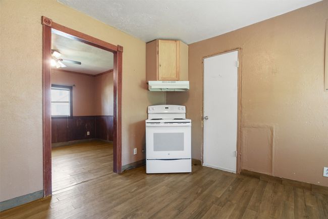 Kitchen featuring baseboards, electric range, under cabinet range hood, light brown cabinetry, and wood finished floors | Image 5