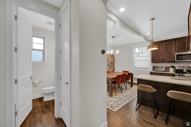 Kitchen featuring appliances with stainless steel finishes, dark brown cabinets, dark wood-style floors, baseboards, and beamed ceiling | Image 23
