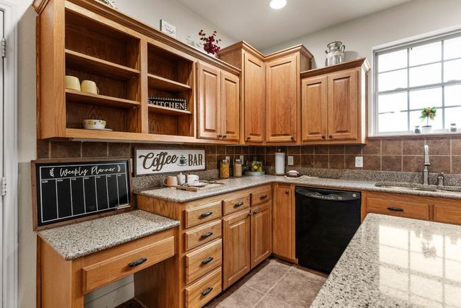 Kitchen with a sink, tasteful backsplash, black dishwasher, and light stone countertops | Image 14