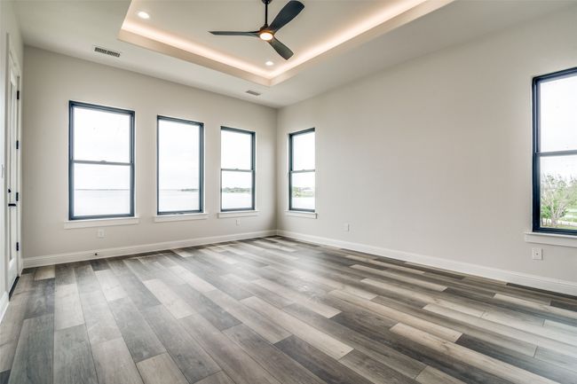 Unfurnished room with a healthy amount of sunlight, wood-type flooring, ceiling fan, and a tray ceiling | Image 14