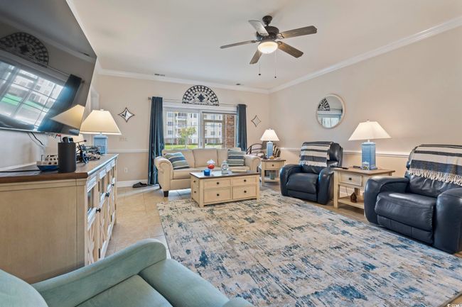 Living room with a ceiling fan, light tile patterned floors, and ornamental molding | Image 11