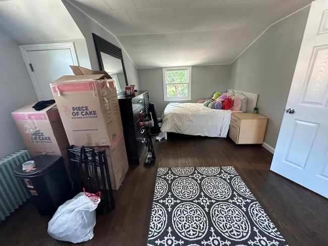 Bedroom featuring vaulted ceiling, radiator heating unit, and wood finished floors | Image 9