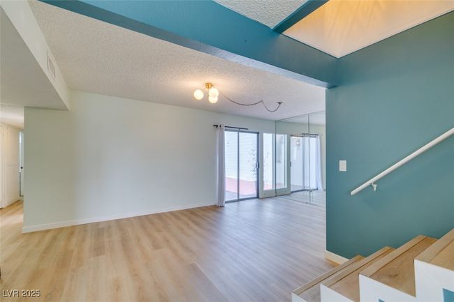 Spare room with light wood-type flooring, a textured ceiling, and stairway | Image 12