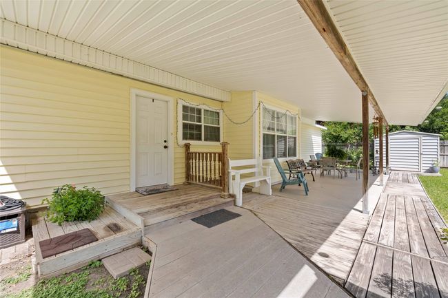 Covered back porch with wooden terrace and outdoor dining area. | Image 28