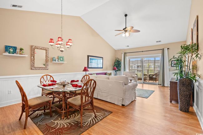 Dining area with a ceiling fan, light wood-style flooring, wainscoting, high vaulted ceiling, and a chandelier | Image 16