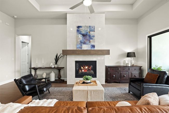Living room featuring wood finished floors, ceiling fan, and a tray ceiling | Image 13