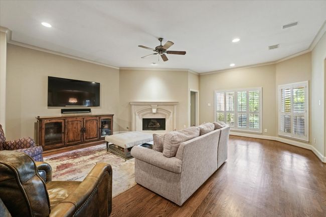 Living area featuring dark wood-style floors, a ceiling fan, crown molding, a fireplace, and recessed lighting | Image 11