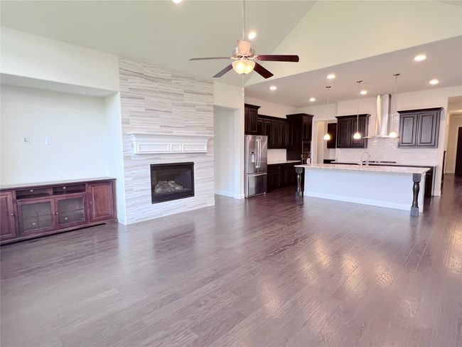 Unfurnished living room with a ceiling fan, recessed lighting, vaulted ceiling, dark wood-style flooring, and a fireplace | Image 17
