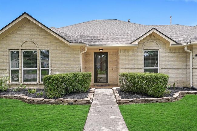 A tidy stone-edged walkway leads to a covered front porch with storm door entry, framed by manicured hedges and symmetrical front-facing windows with brick arch details—creating a warm, welcoming first impression. | Image 4