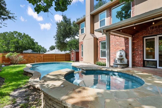 View of pool with a fenced backyard, a storage unit, a pool with connected hot tub, and a patio area | Image 34