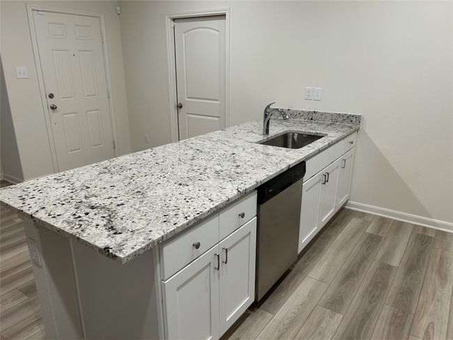 Kitchen with white cabinetry, a peninsula, light wood-style flooring, a sink, and dishwasher | Image 11