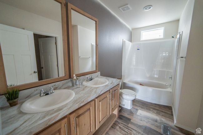Full bathroom featuring toilet, wood finished floors, a sink, and visible vents | Image 62