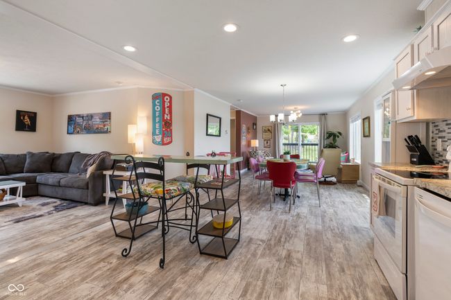 living area featuring light wood finished floors, a chandelier, ornamental molding, and recessed lighting | Image 8