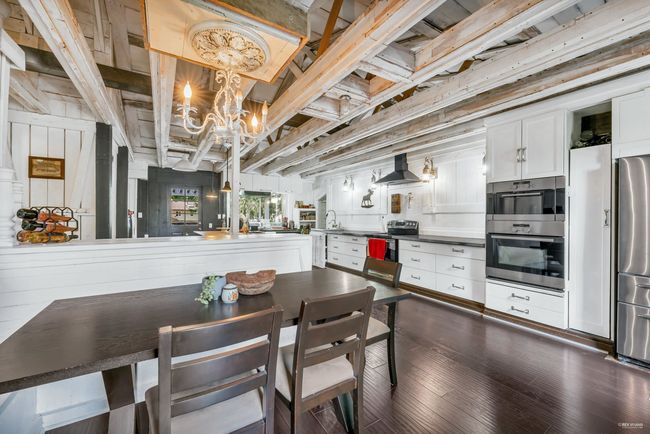 Dining area with a notable chandelier and dark wood-style floors | Image 5