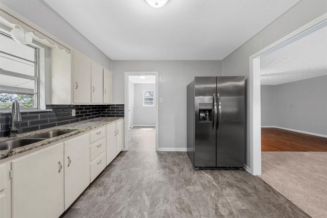 Kitchen with stainless steel fridge with ice dispenser, decorative backsplash, white cabinets, and light stone counters | Image 8