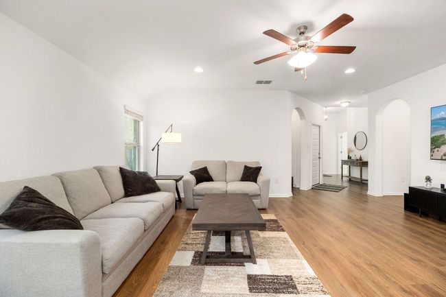 Living area with arched walkways, a ceiling fan, wood finished floors, and recessed lighting | Image 7