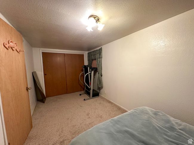 Bedroom featuring a textured ceiling, light carpet, and a closet | Image 23