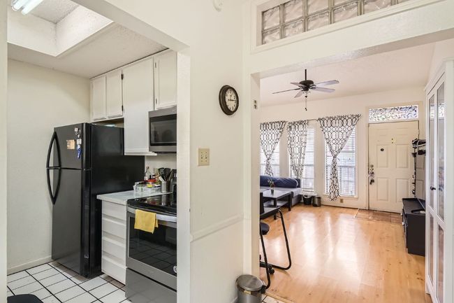 Kitchen featuring appliances with stainless steel finishes, light countertops, white cabinetry, light wood-type flooring, and a ceiling fan | Image 11
