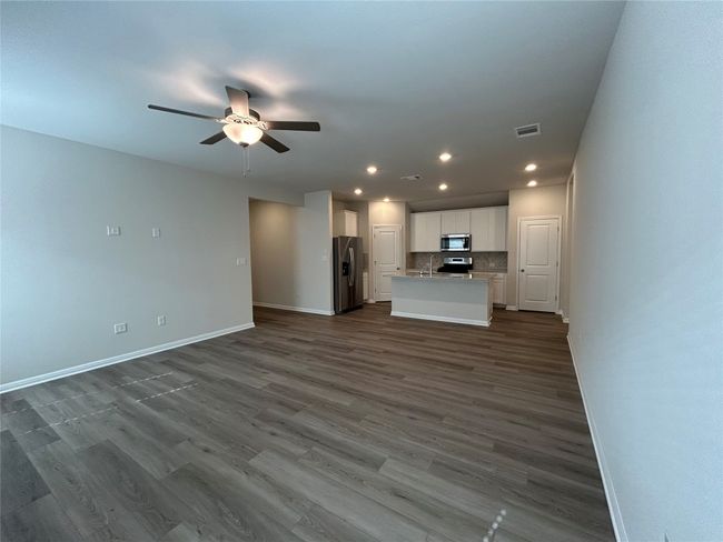 Unfurnished living room featuring a ceiling fan, recessed lighting, and dark wood-style floors | Image 8