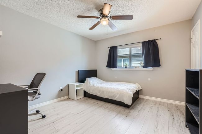 Bedroom with a textured ceiling, baseboards, wood finished floors, and ceiling fan | Image 18