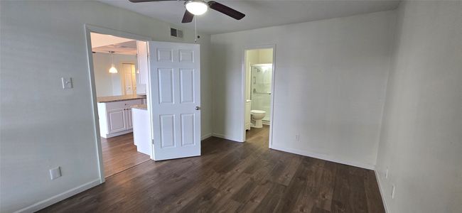 Unfurnished bedroom featuring dark wood-type flooring, ensuite bath, and a ceiling fan | Image 9